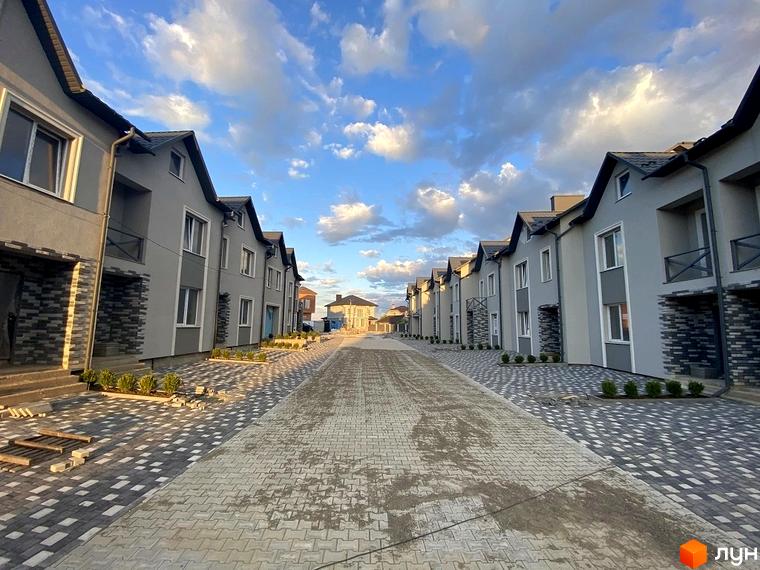 Таунхауси Hodillywood 2.0 з сірими фасадами та бруківкою на прибудинковій території. Зовнішній вигляд будинків та доглянута територія.