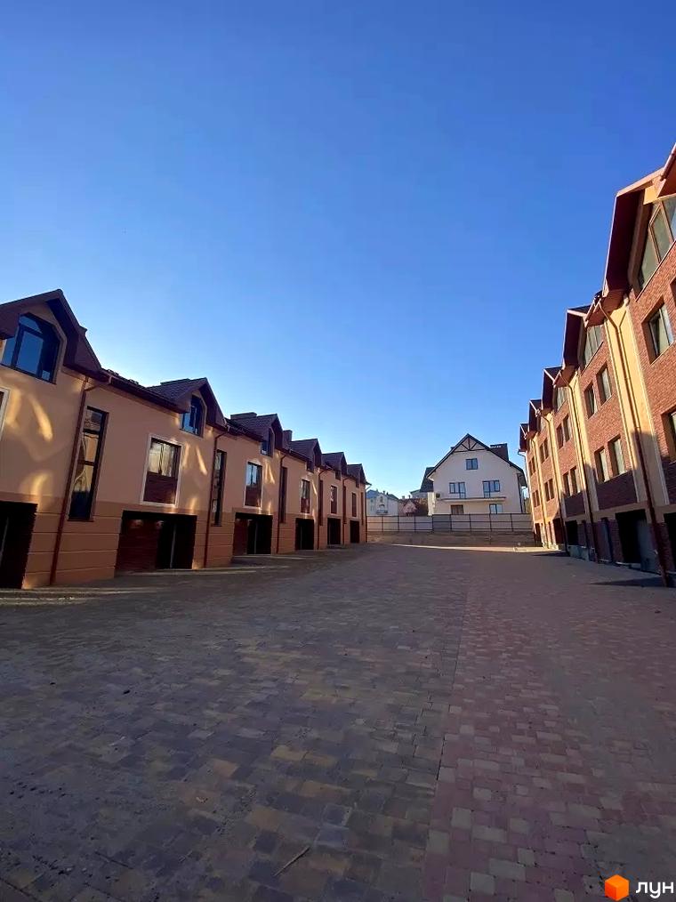 Таунхауси Hodillywood 4.0 – це двоповерхові будинки з коричневими дахами та світлими фасадами, розташовані на бруківці.