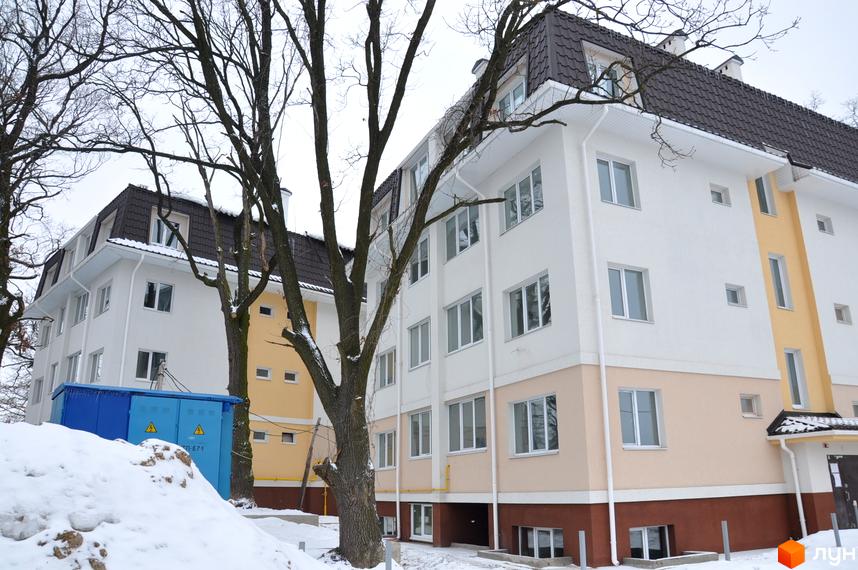 Житловий комплекс ЖК Ворзель з білими та жовтими фасадами, оточений деревами та снігом на прибудинковій території.