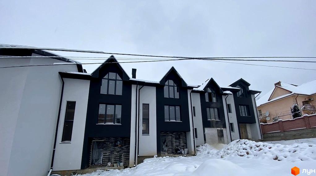 Таунхауси Hodillywood 5.0 - фасади будівель з великими вікнами, оздоблені білою та чорною штукатуркою, на тлі зимового пейзажу.