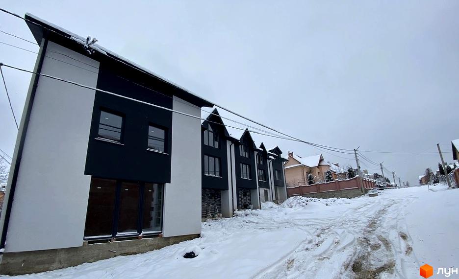 Зовнішній вигляд таунхаусів Hodillywood 5.0 у зимовий період з засніженою прибудинковою територією. Новобудова з чорно-білими фасадами та великими вікнами.