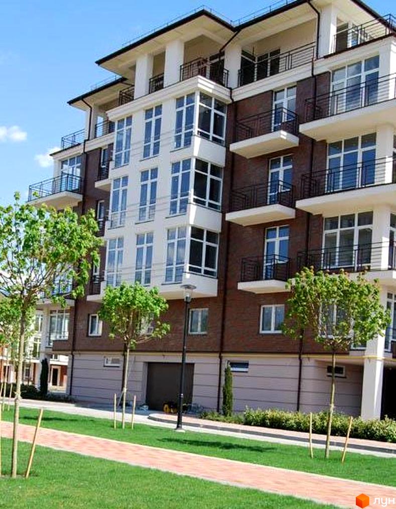 Житловий комплекс Сонячний промінь з сучасними балконами та зеленими насадженнями на прибудинковій території.