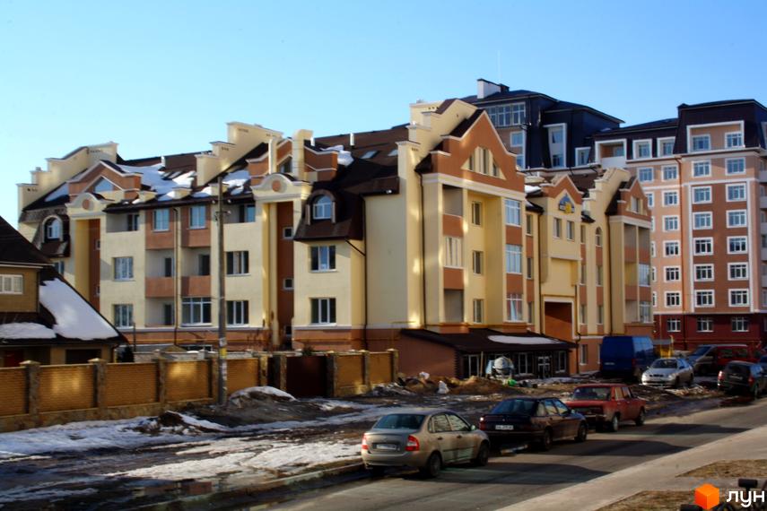 Житловий комплекс на вул. Богдана Хмельницького, 15-17 з сучасною архітектурою. Прибудинкова територія з автомобілями та зимовим покриттям.