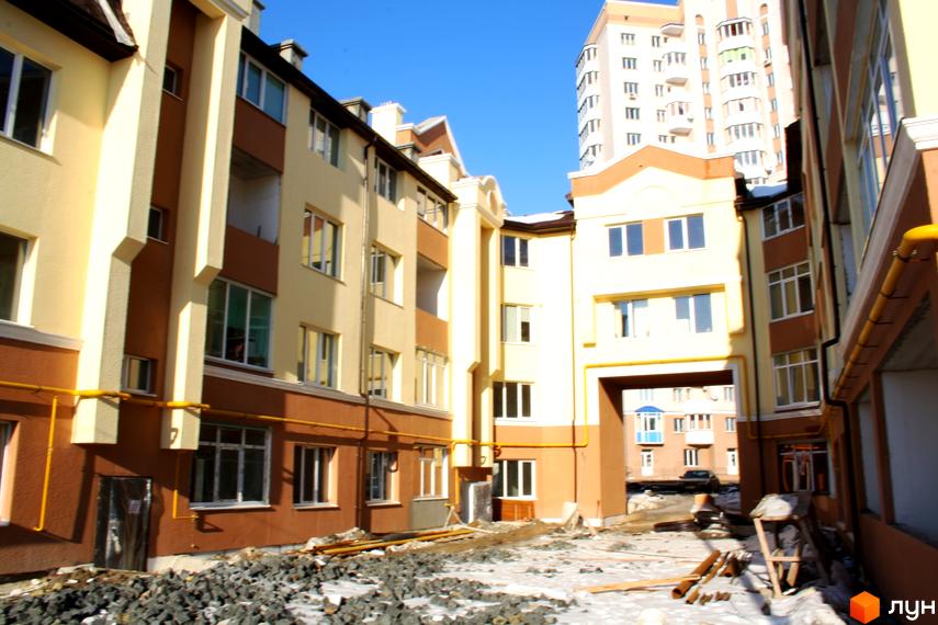 Житловий комплекс на вул. Богдана Хмельницького, 15-17 з фасадом жовто-коричневих відтінків. Прибудинкова територія в процесі облаштування.