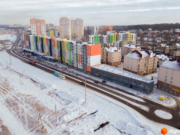 Житловий комплекс Синергія-3+ у зимовому пейзажі. Сучасні багатоповерхові будинки з яскравими фасадами та прибудинкова територія, вкрита снігом.