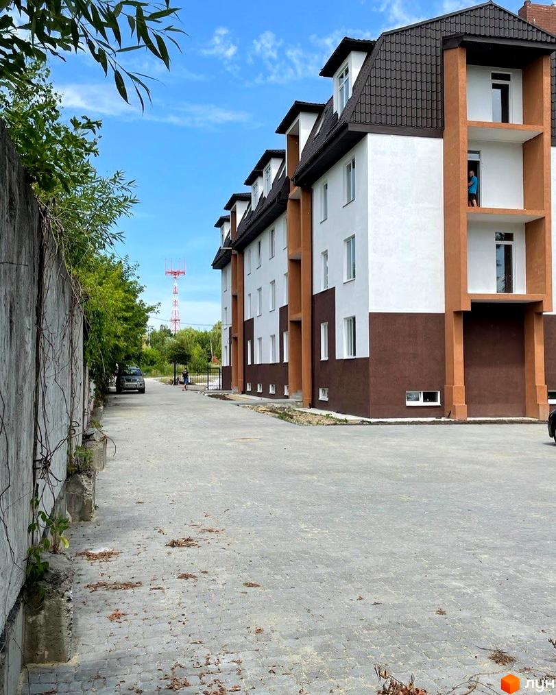 Зовнішній вигляд будинку в Житловому районі Три шоколади. На фото прибудинкова територія з тротуаром та зеленими насадженнями.