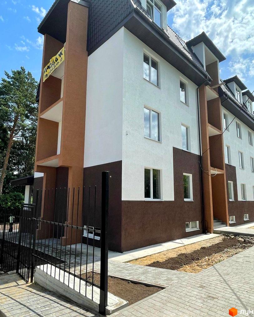 Зображення фасаду будинку в Житловому районі Три шоколади. На фото видно частину прибудинкової території з тротуарною плиткою та огорожею.