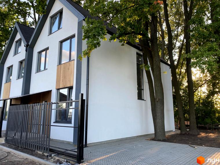 Білосніжні дуплекси «Дубки» з панорамними вікнами та дерев'яними вставками на фасаді. На прибудинковій території висаджені дерева та облаштована бруківка.