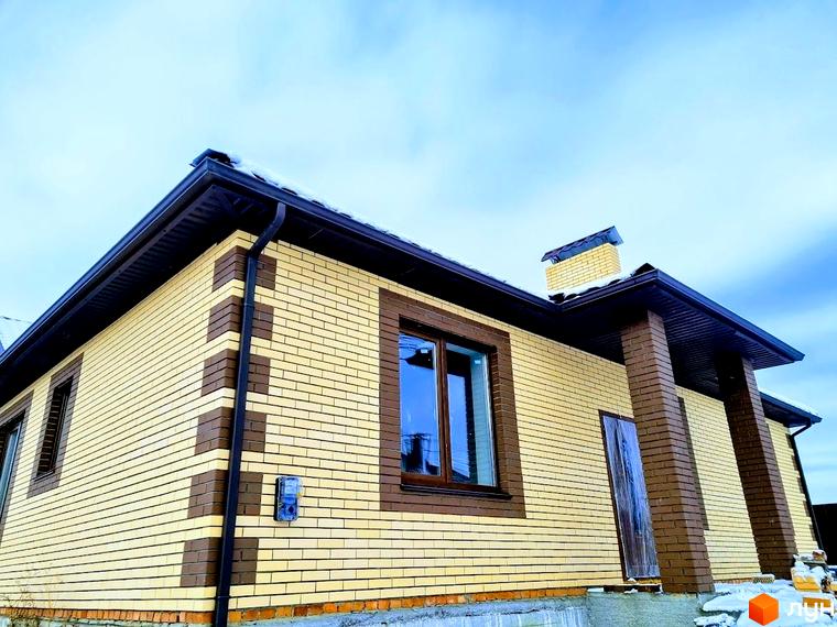 Будинок в Котеджному містечку Green city з фасадом зі світло-жовтої цегли та темно-коричневими елементами. На даху та навколо будинку видно сніг.