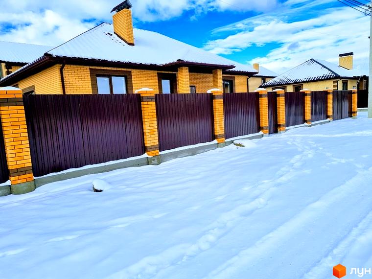 Будинки Котеджного містечка Green city з жовтої цегли з коричневими дахами, вкритими снігом. Перед будинками коричневий паркан та засніжена територія.