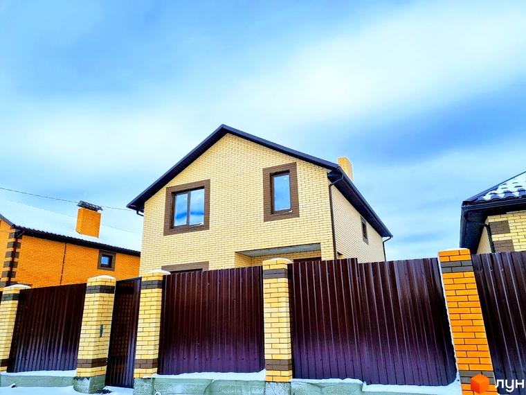 Котеджне містечко Green city: двоповерховий будинок з жовтої цегли та коричневим дахом. Огородження з профнастилу та цегляних стовпів, засніжена прибудинкова територія.