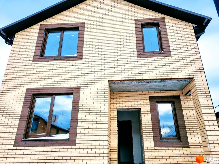 Будинок Котеджного містечка Green city з фасадом зі світлої цегли та коричневими віконними рамами. Видно вхід та дах.