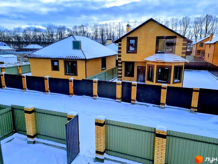 Два цегляні будинки жовтого кольору з темними дахами та вікнами в Котеджному містечку Green city. Територія та огорожі вкриті снігом.