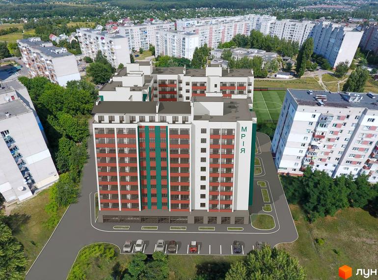 Житловий комплекс Мрія – це багатоповерхова новобудова з червоно-білими фасадами та зеленою смугою, розташована біля футбольного поля та паркування.