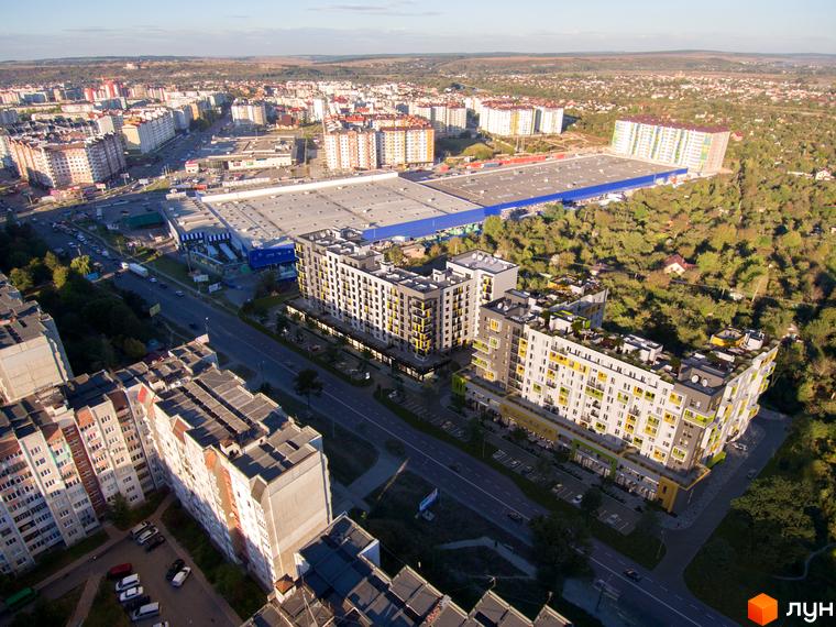 Житловий комплекс Стожари має багатоповерхові будинки з жовтими та сірими фасадами, балконами та терасами. На прибудинковій території є парковка та зелені насадження.