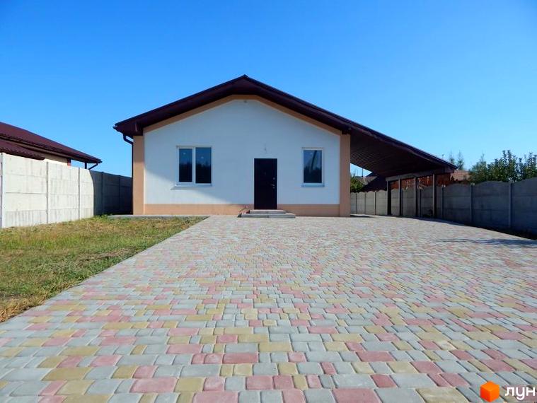 Одноповерховий будинок з двома вікнами та темними дверима. Передня частина будинку викладена бруківкою, поруч розташований навіс для автомобілів.