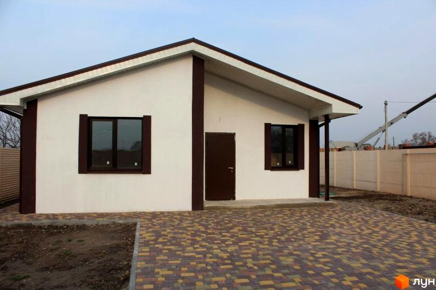 Одноповерховий будинок з коричневими вікнами та дверима. Передня частина будинку викладена бруківкою.