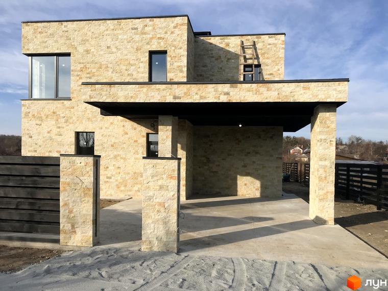 Фасад будинку КМ Eco-residence Нові Безрадичі з облицюванням з каменю. На території розташована парковка та огорожа.