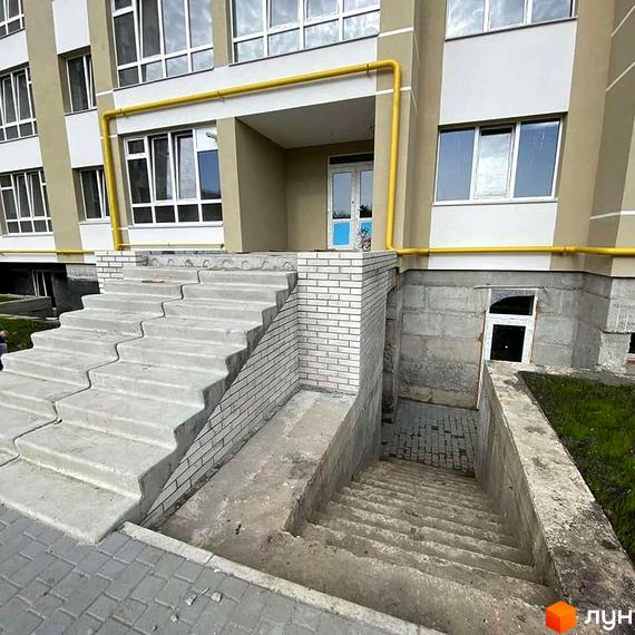 Зовнішній вигляд будинку житлового комплексу на вул. Зарічанська, 3/3б, з бетонними сходами та цегляним оздобленням. Прибудинкова територія з газоном та бруківкою.