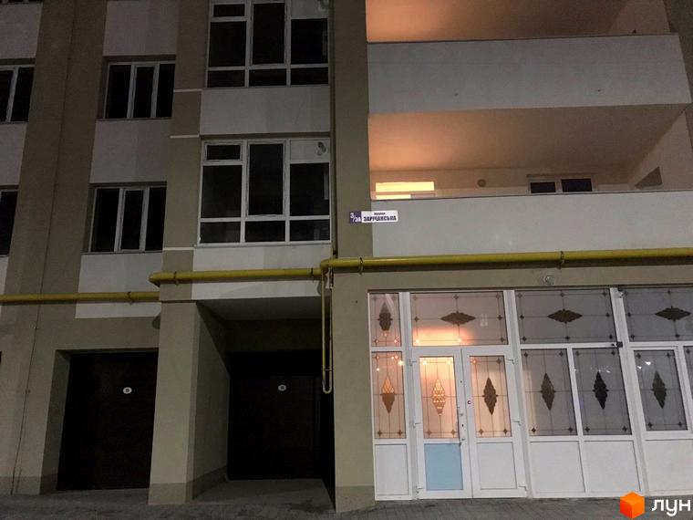Фасад багатоповерхового будинку. На першому поверсі вхідна група з скляними дверима. Адреса: вул. Зарічанська, 3/3а.