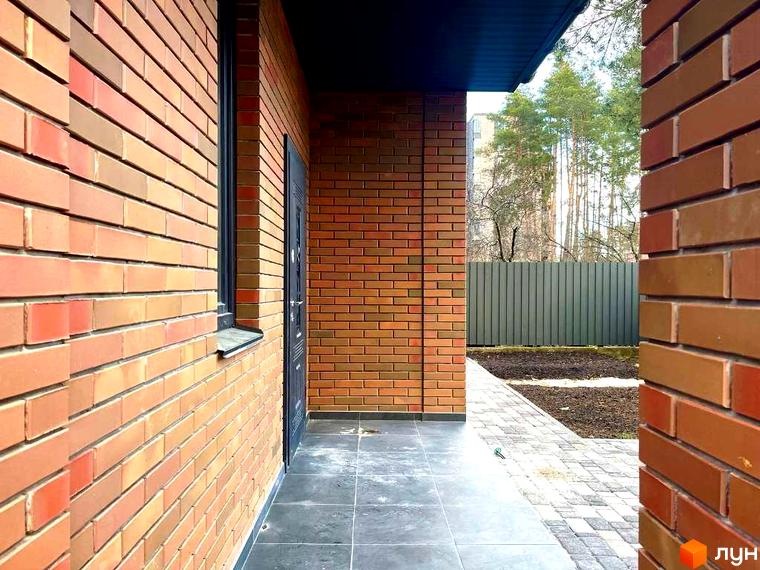 КМ Дубовий Гай: фасади будівель з цегли та прибудинкова територія з доріжками та парканом. Зовнішній вигляд новобудови та її оточення.