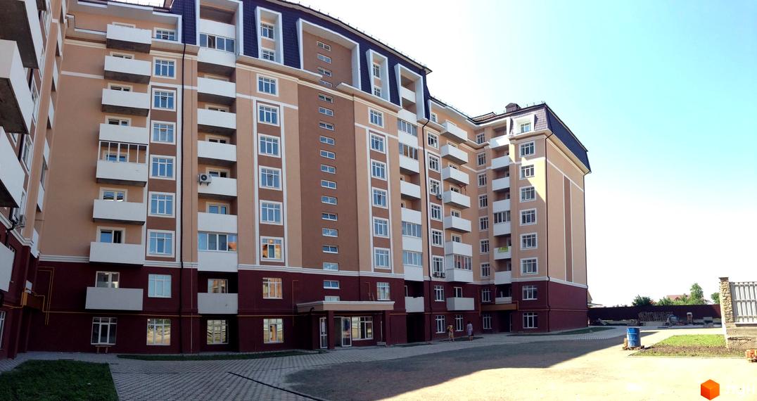 Житловий комплекс ЖК Варшавський двір - багатоповерховий будинок з балконами та кондиціонерами, прибудинкова територія з бруківкою та зеленню.