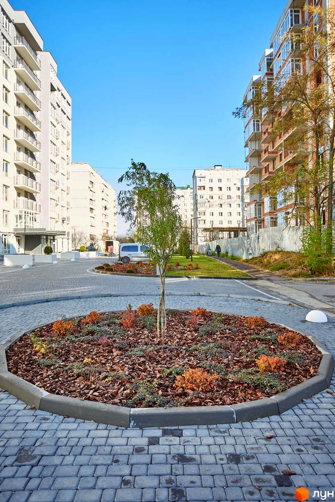 Зображення фасаду та прибудинкової території Житлового комплексу KromaxBud. Вигляд новобудови та ландшафтного дизайну з деревами.