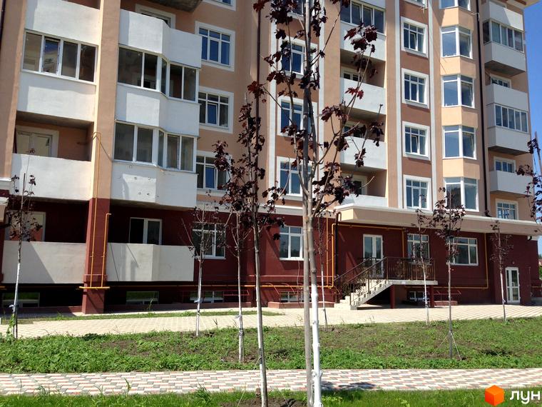 Житловий комплекс Варшавський двір - багатоповерховий будинок з балконами та вікнами, прибудинкова територія з деревами та доріжками.