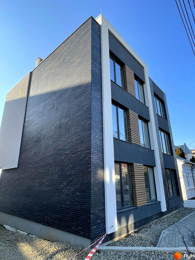 Зовнішній вигляд будинку в Житловому комплексі Elite House. Фасад оздоблено цеглою, великі вікна та білі колони.