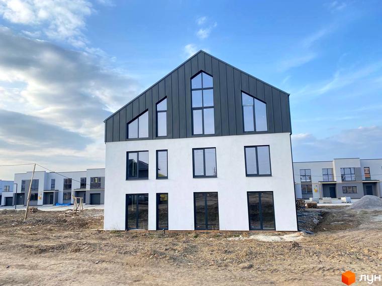 Новобудова ЖК Струмочок 2 з білим фасадом та сірим дахом. Навколо будинку триває будівництво, видно ґрунт та інші будинки комплексу.