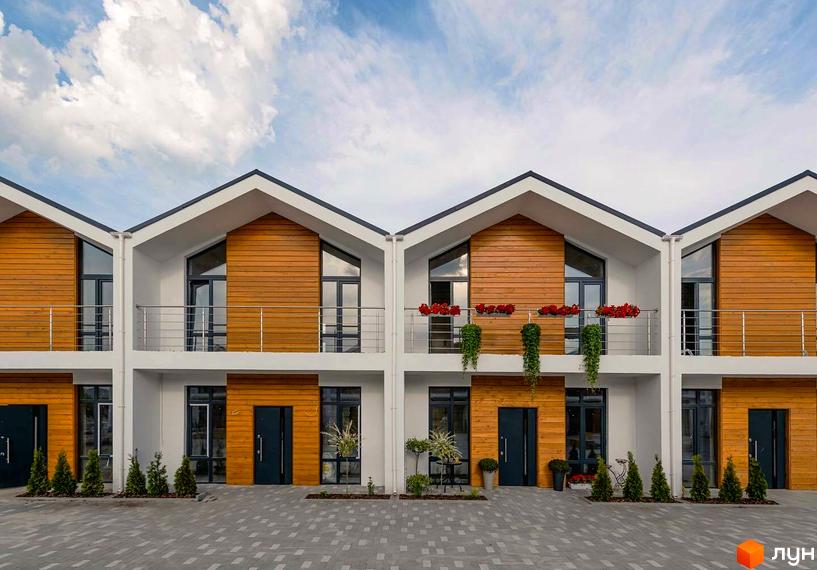 Зображення фасаду будинку КМ Екохаус з дерев'яним оздобленням, балконами та вікнами. На передньому плані бруківка та зелені насадження.