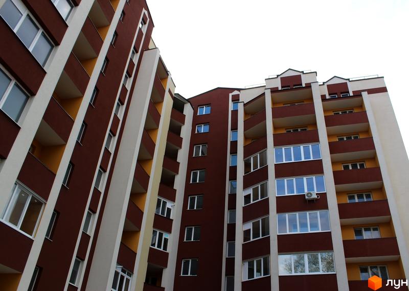 Багатоповерховий житловий комплекс на вулиці Пирогова з коричневим фасадом, білими вертикальними елементами та жовтими балконами.