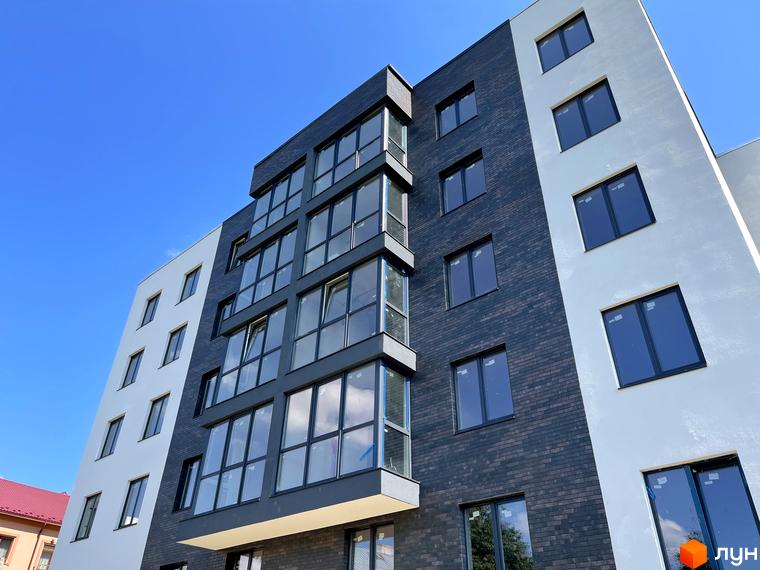 Фасад житлового комплексу Center з білою та темно-сірою цегляною обробкою та великими вікнами. Будинок має багатоповерхову структуру з чіткими лініями.