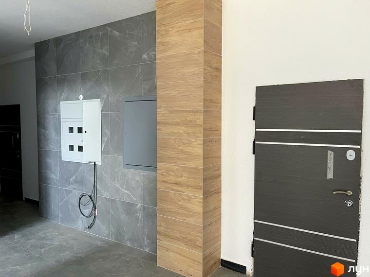 Зовнішній вигляд входу в ЖК Center з дверима та електрощитовою. Опис прибудинкової території відсутній.