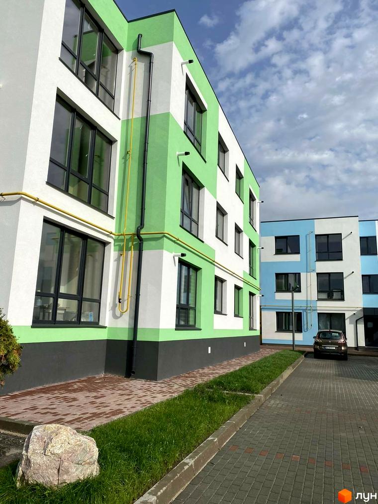 Житловий комплекс Стайл Хаус з яскравим фасадом та доглянутою прибудинковою територією з бруківкою та зеленню.