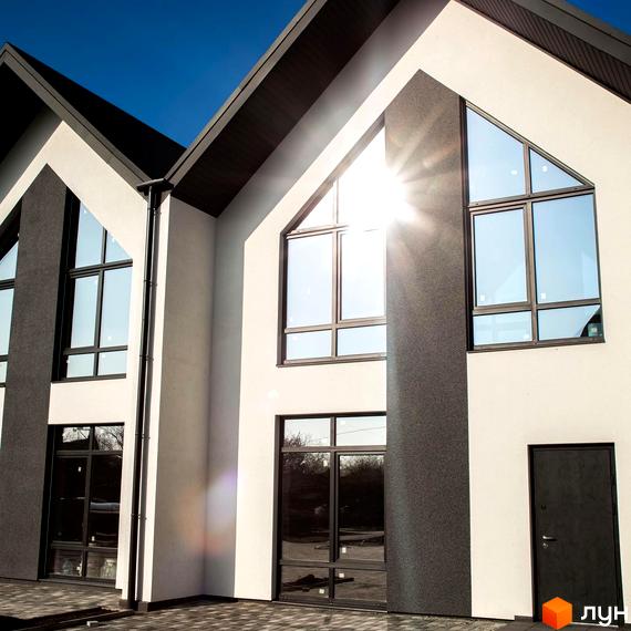 Фасади таунхаусів Scandi Village з білими стінами, темними дахами та великими панорамними вікнами. Прибудинкова територія вимощена бруківкою.