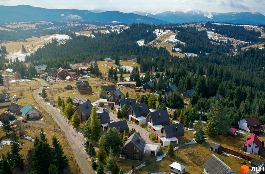 Котеджне містечко SHANA.villas з будинками з темними дахами та світлими фасадами, розташоване серед лісових пагорбів та гір.