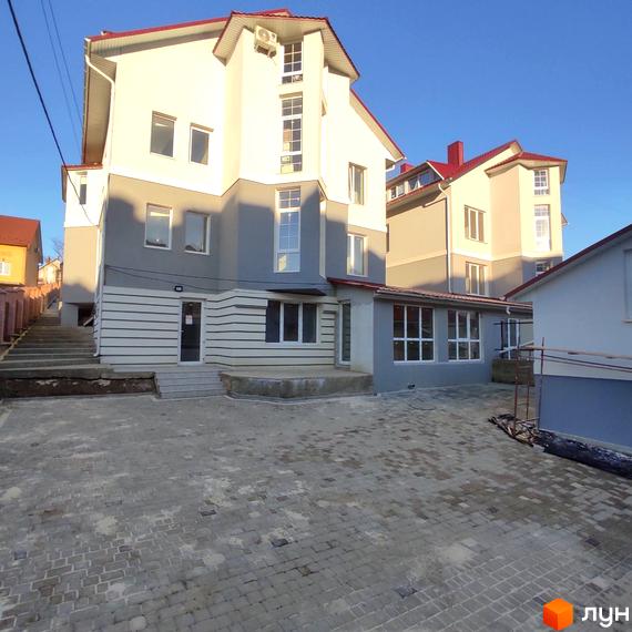 Житловий комплекс на вул. Мазепи, 30 з біло-сірим фасадом та червоним дахом. Прибудинкова територія вимощена бруківкою.