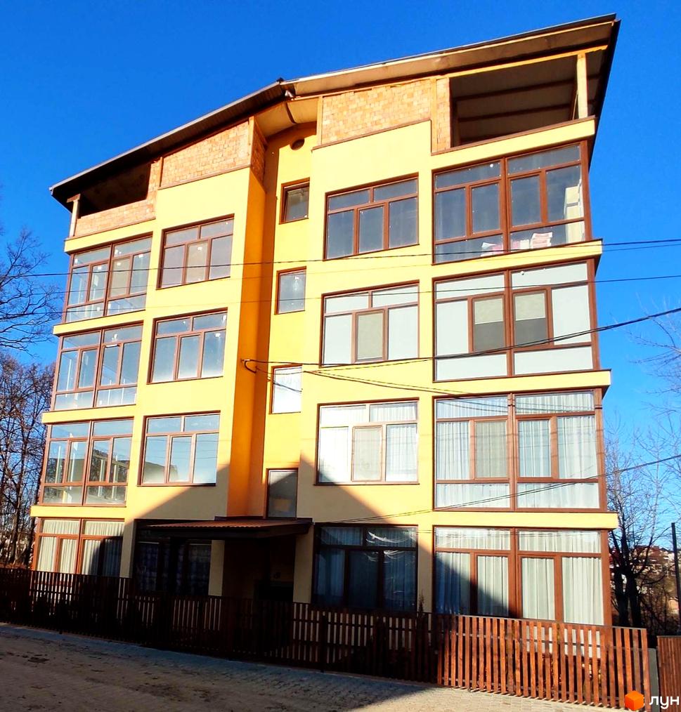 Зовнішній вигляд будинку в Житловому комплексі Міжнародний. Багатоповерхова будівля з великими вікнами та коричневою огорожею.