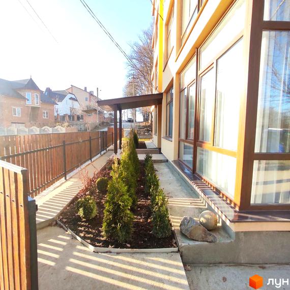 Зовнішній вигляд будинку в Житловому комплексі Міжнародний. Прибудинкова територія з деревами та ландшафтним дизайном.