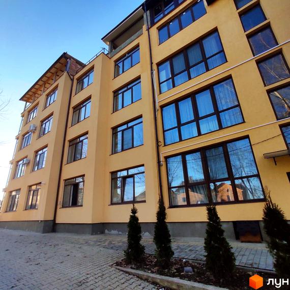 Зовнішній вигляд Житлового комплексу Міжнародний, багатоповерховий будинок з великими вікнами. На передньому плані висаджені декоративні дерева.