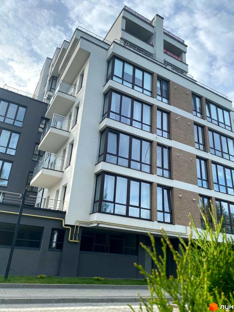 Зовнішній вигляд новобудови ЖК Бульвар Європейський з великими вікнами та балконами. Навколо будинку зелена галявина та тротуар.