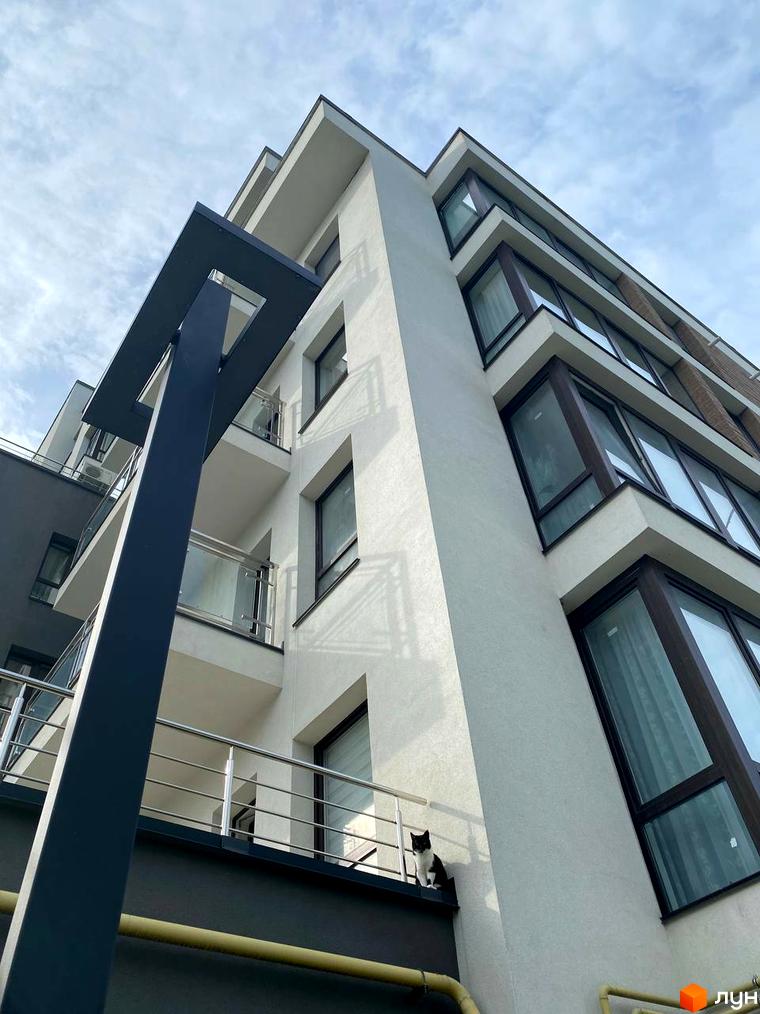 Зовнішній вигляд новобудови ЖК Бульвар Європейський з балконами та вікнами. На одному з балконів сидить кіт.