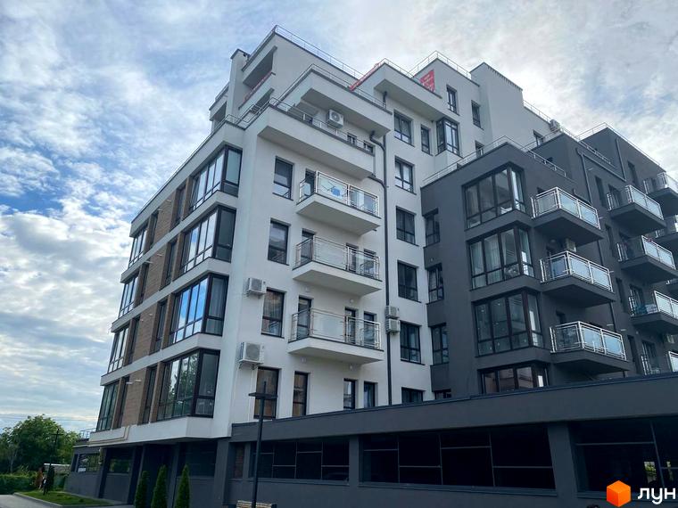 Житловий комплекс Бульвар Європейський. Зовнішній вигляд новобудови з білими та сірими фасадами, великими вікнами та балконами. Навколо будинку зелені насадження та елементи прибудинкової території.