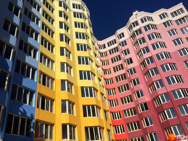 Житловий комплекс Святопетрівський: багатоповерховий будинок з вигнутим фасадом, пофарбований у синій, жовтий, помаранчевий та рожевий кольори.