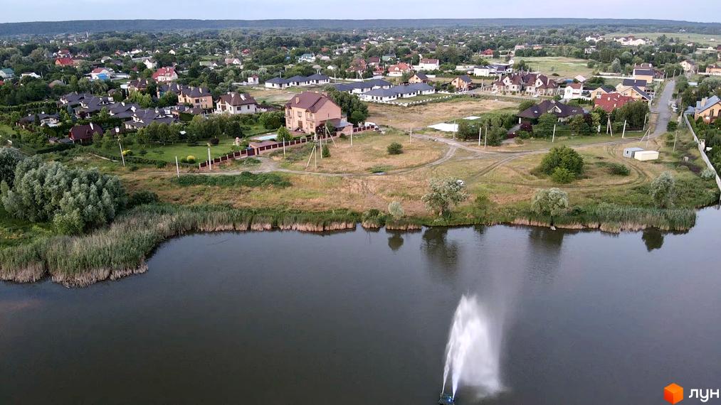 Вид на Котеджне містечко Зоряний з висоти пташиного польоту: будинки з темними дахами та доглянута прибудинкова територія з озером.