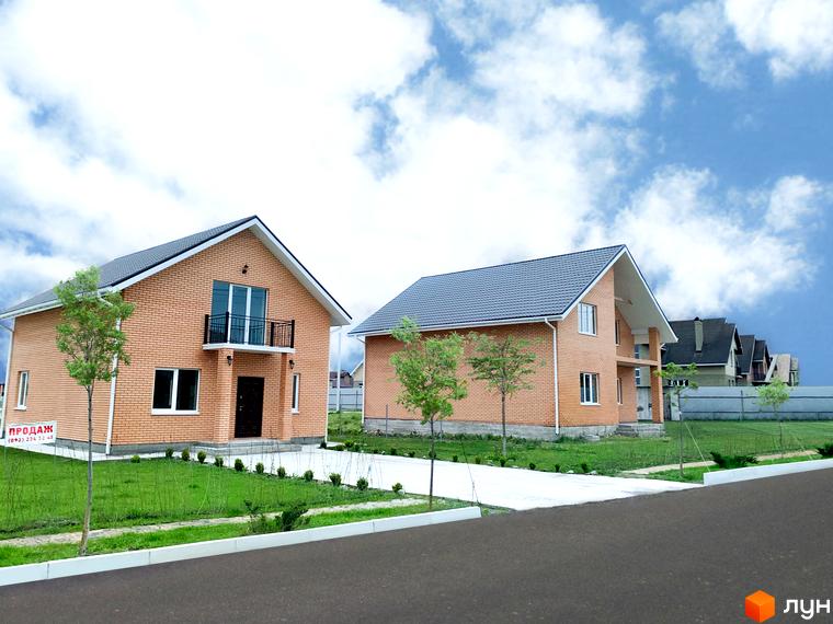 Двоповерхові будинки з цегляними фасадами та темними дахами в Котеджному містечку Зоряний. На території є зелені газони та асфальтована дорога.