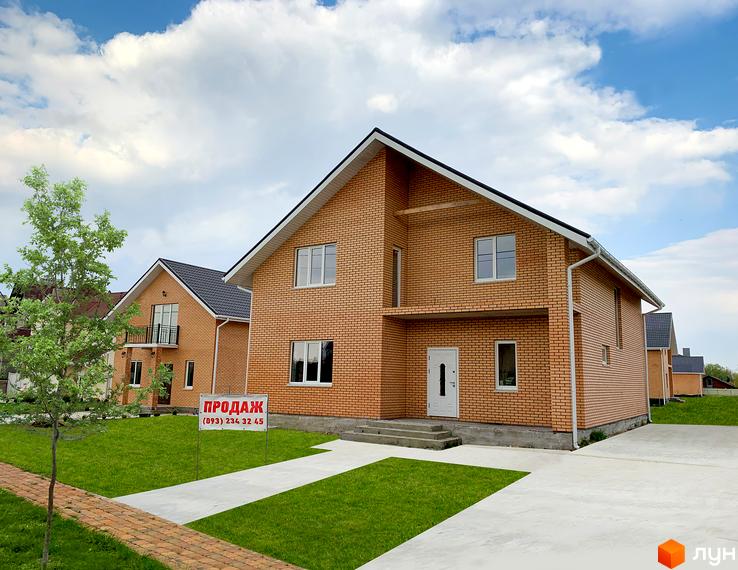 Цегляний будинок в Котеджному містечку Зоряний з газоном та доріжками. На передньому плані табличка з написом «Продаж».
