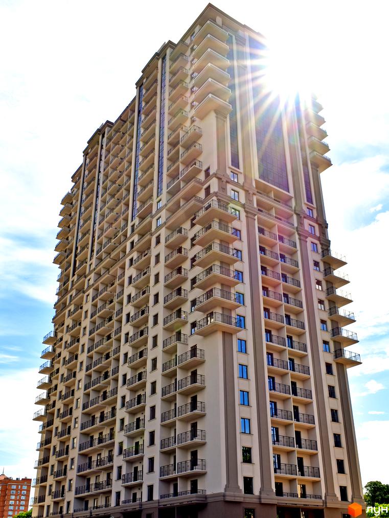 Житловий комплекс Акрополь: високий багатоповерховий будинок зі світлим фасадом, численними балконами, освітлений яскравим сонцем.