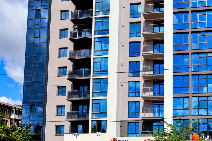 Фасад житлового комплексу Park Residence з великою кількістю скління та балконами. Будинок має сучасний вигляд із сірими та білими елементами.